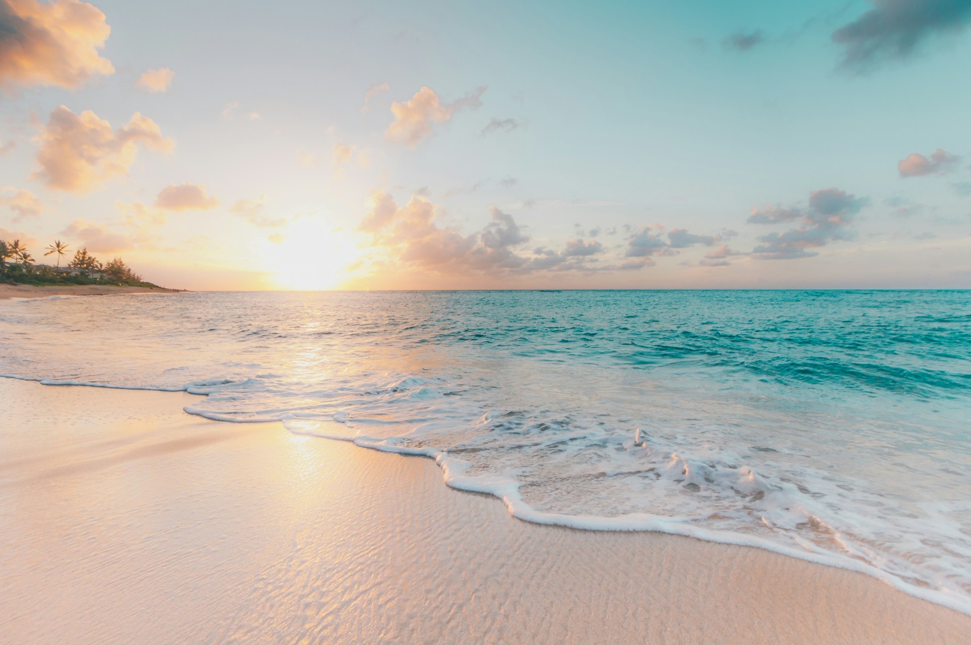 Small waves washing onto a sandy beach at sunset