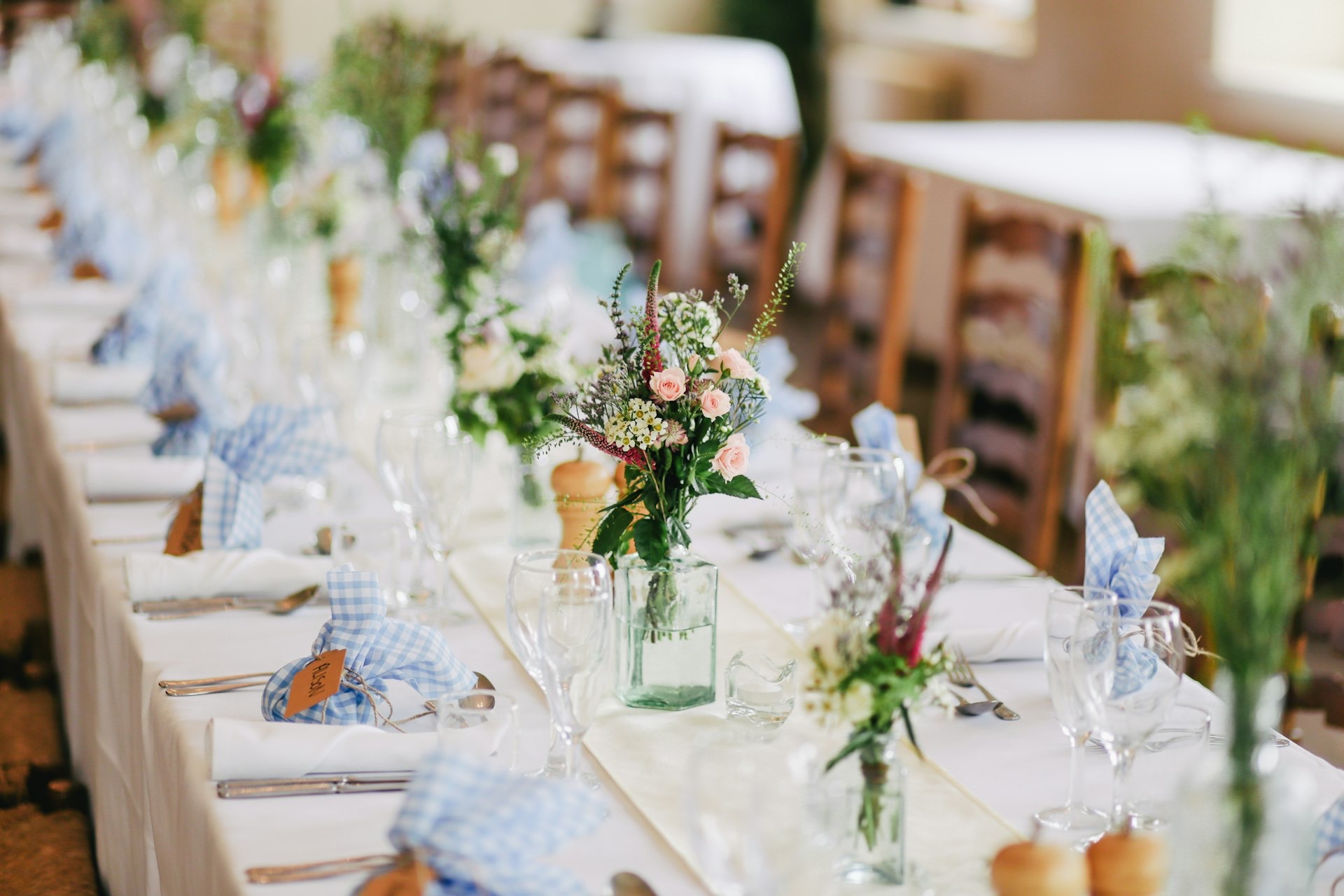 Long wedding reception tables set with flowers and glassware