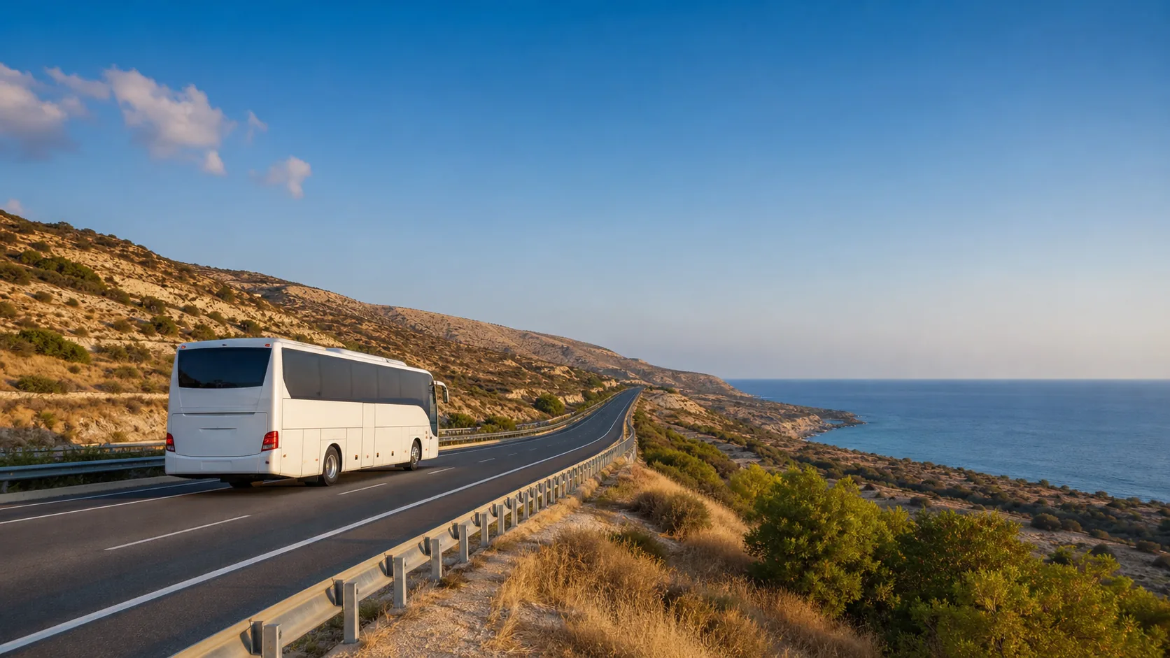An unbranded white airport shuttle coach travelling along a coastal Cyprus road