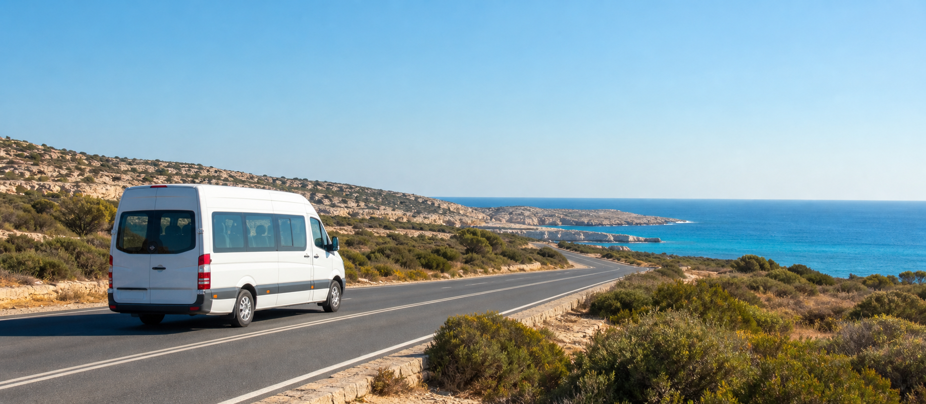 A white airport shuttle travelling along a coastal road towards the Mediterranean in south-east Cyprus