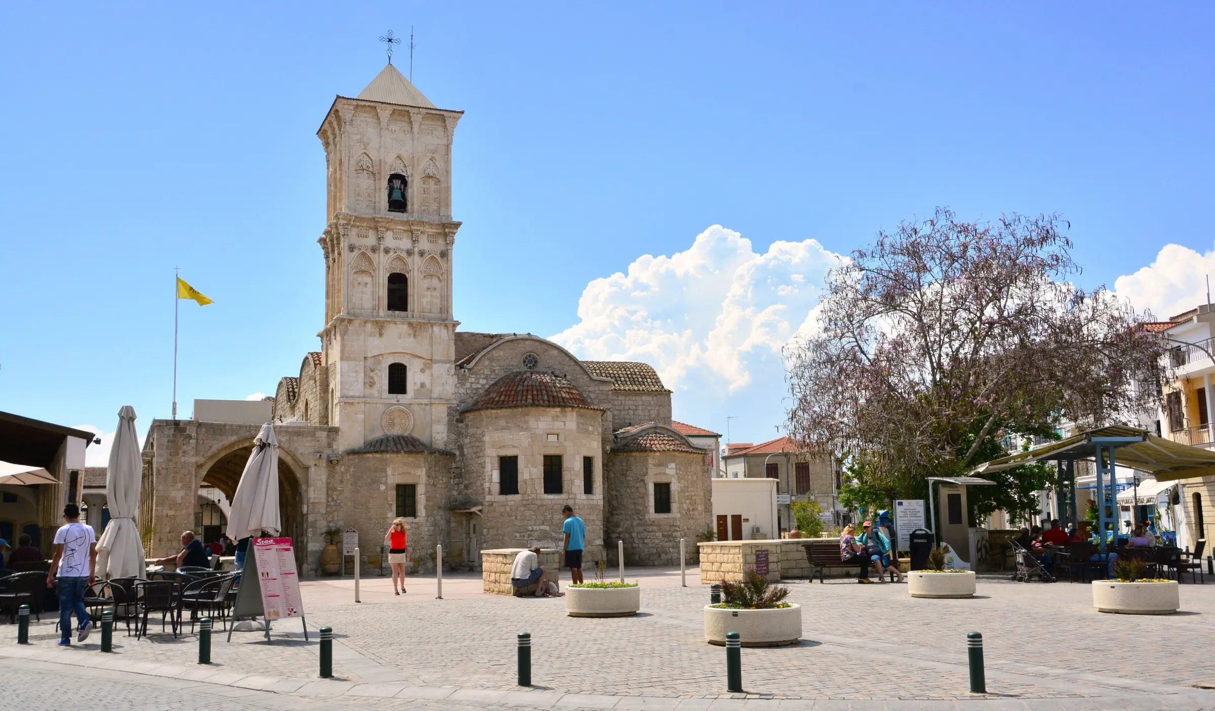 The stone bell tower of the Church of Saint Lazarus rising above its café-lined square in Larnaca