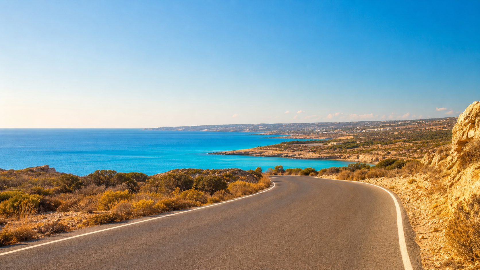 A quiet coastal road curving towards blue Mediterranean water on the south-east coast of Cyprus
